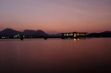 Dark luxury overwater villa with soft reflections on still water at dusk.