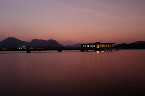 Dark luxury overwater villa with soft reflections on still water at dusk.