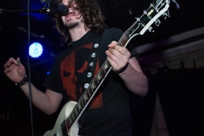 Front view of a black t-shirt with a vintage rock band skull design in white and red accents