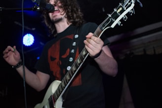 Front view of a black t-shirt with a vintage rock band skull design in white and red accents