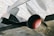 The image depicts a close-up view of a jet aircraft's engine and exhaust area. The aircraft is metallic and appears to be housed in a large hangar or museum with a grid-like ceiling structure. Part of an insignia or logo is visible on the aircraft's body.