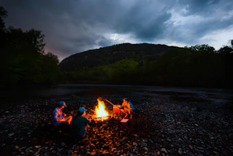 A candid shot of a small group gathered in prayer around a campfire at dusk in Montana.