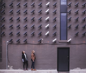 two women facing security camera above mounted on structure