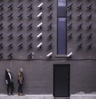 two women facing security camera above mounted on structure