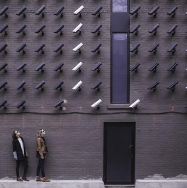 two women facing security camera above mounted on structure