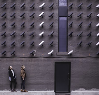 two women facing security camera above mounted on structure