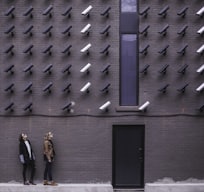 two women facing security camera above mounted on structure