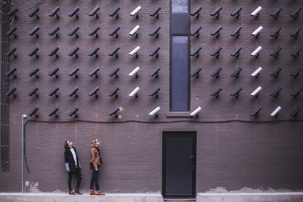 Women viewing modern art with black and white surveillance cameras on wall in Toronto