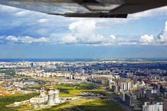 A vibrant aerial view of a sprawling apogee foundry city rising from the desert, with modular rings and lush green agricultural zones powered by small modular reactors.