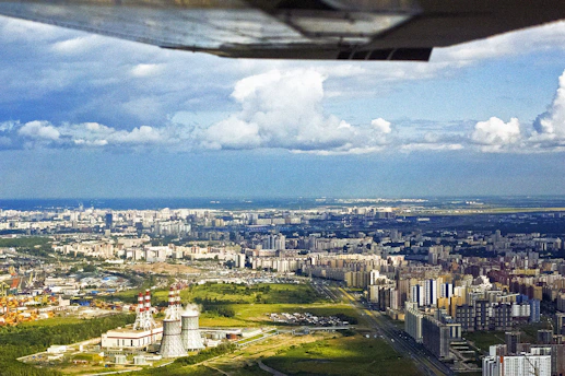 A vibrant aerial view of a sprawling apogee foundry city rising from the desert, with modular rings and lush green agricultural zones powered by small modular reactors.