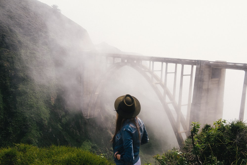 Mujer mirando el puente de hormigón gris con niebla