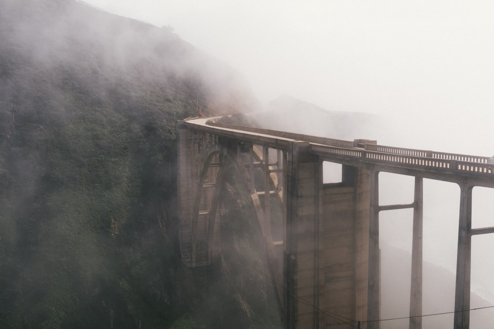 névoa e ponte cinza perto da montanha