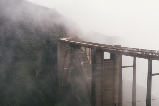 mist and gray bridge near mountain in Bixby Creek Arch Bridge United States