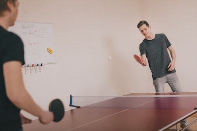 two men playing ping-pong inside room table tennis zoom background
