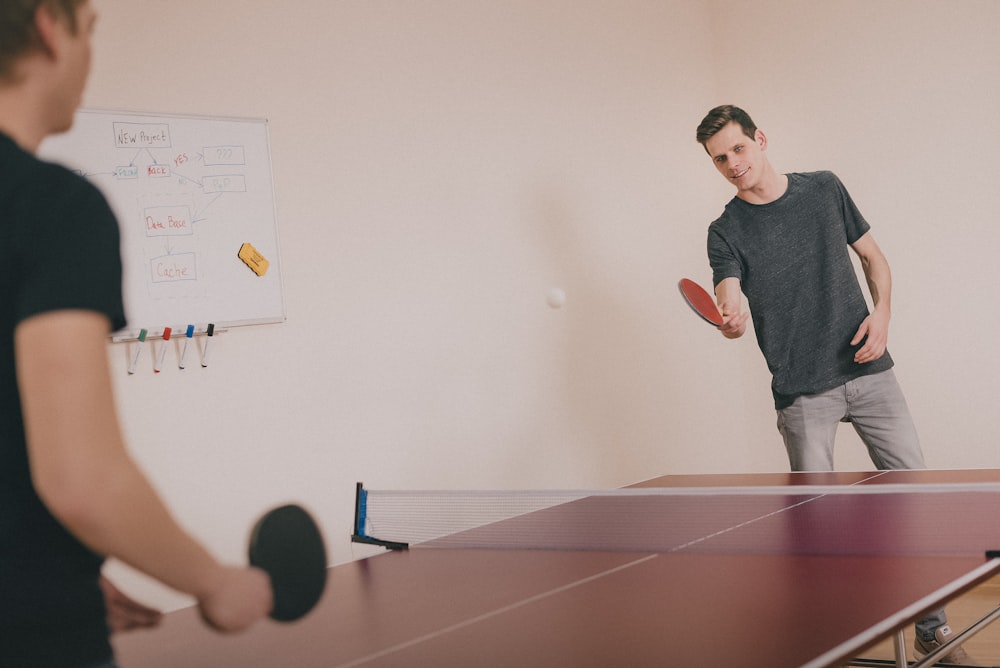 Dos hombres jugando al ping-pong dentro de la habitación