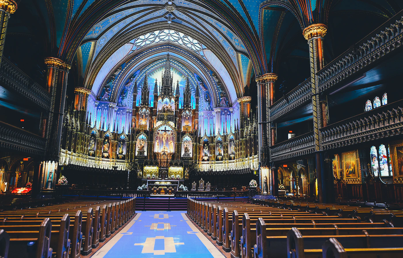 Notre-Dame Basilica of Montreal interior from the back of the nave, the full ceremonial depth visible with blue vaulted ceilings overhead and the golden altar at the far end