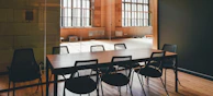 A large wooden conference table surrounded by ergonomic chairs in a cozy room.
