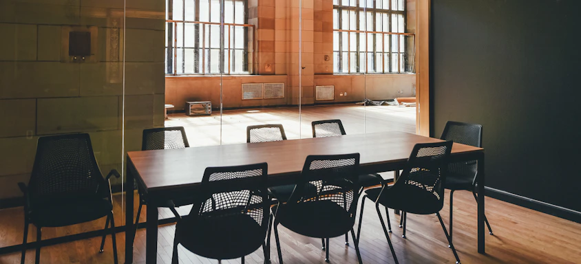 A sleek modern conference room with a large custom-designed table bathed in natural light.