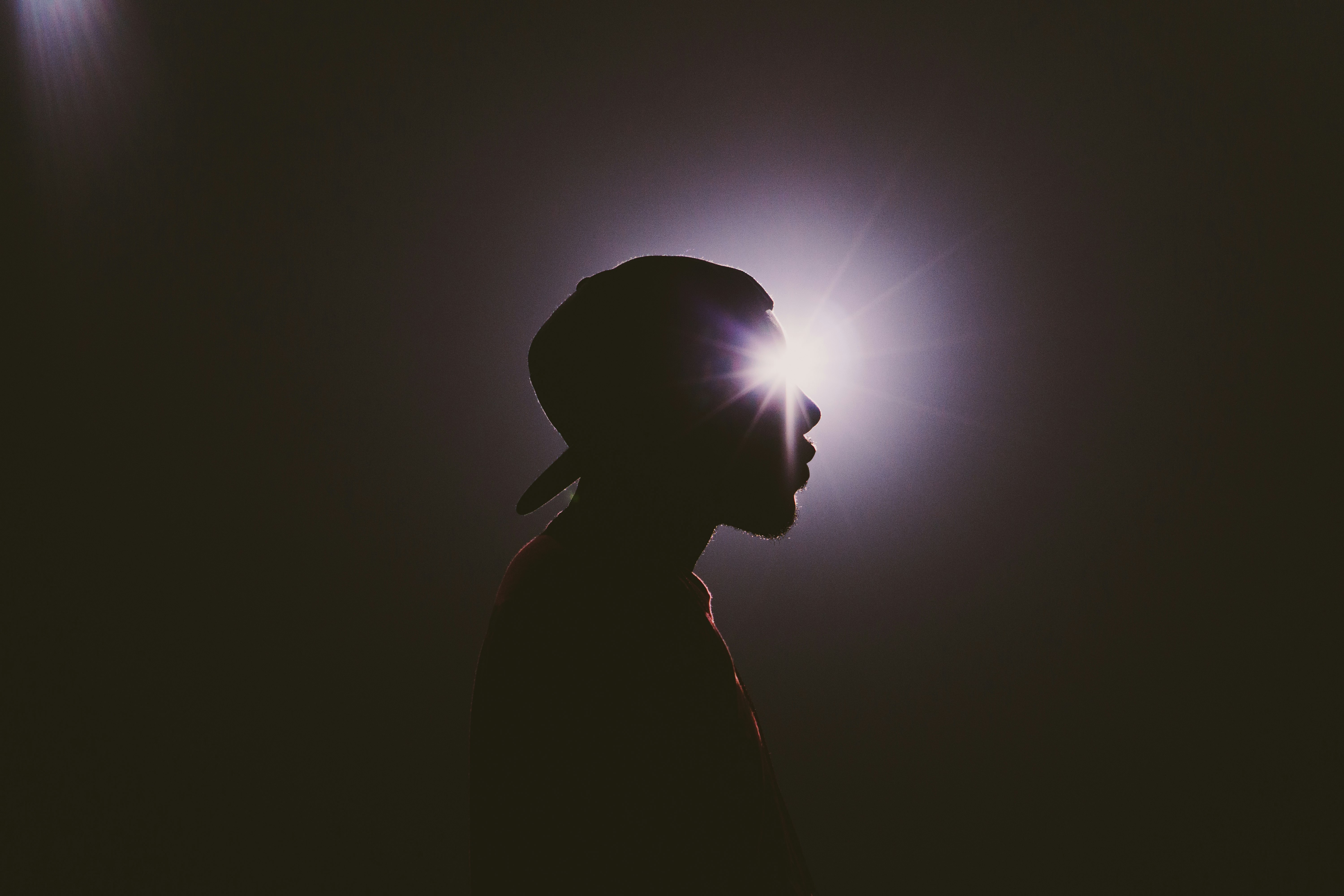 silhouette photography of man wearing cap