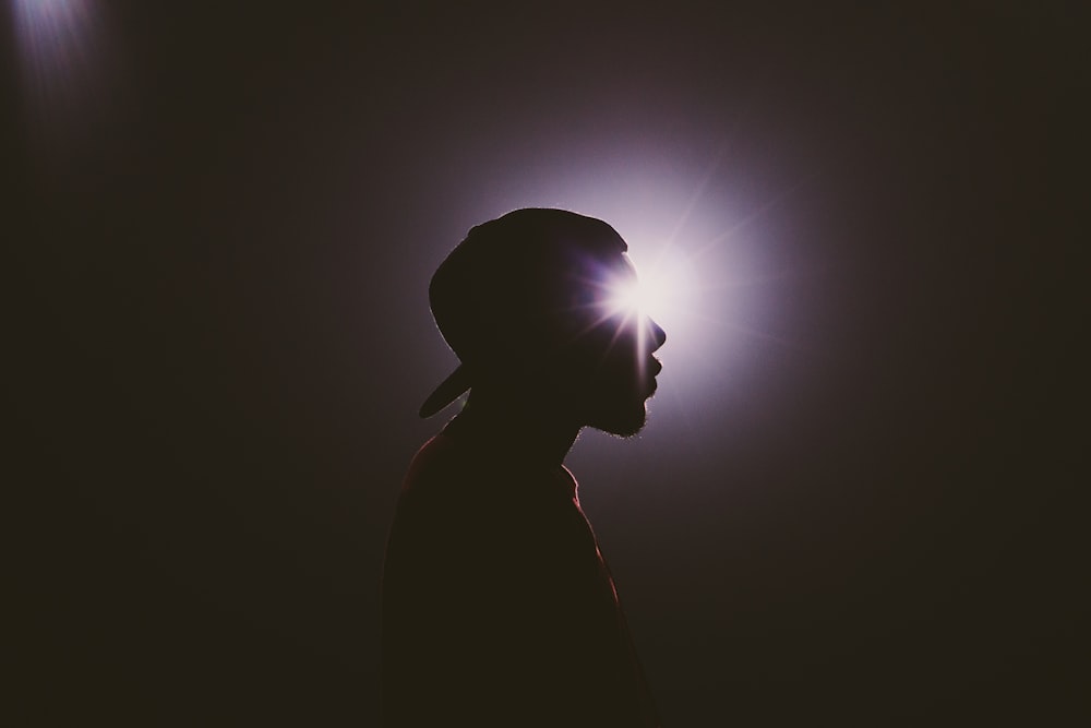 silhouette photography of man wearing cap