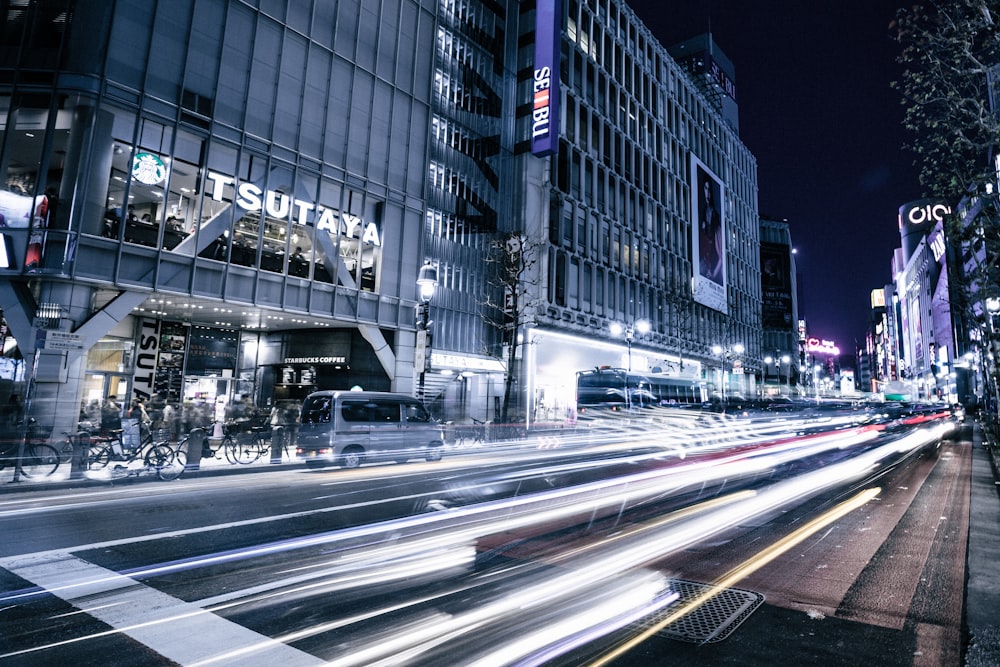 Photographie en accéléré d’une route asphaltée près des bâtiments pendant la nuit