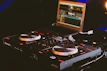Alpha Theta DJ gear setup with laptop and mixing software in the background