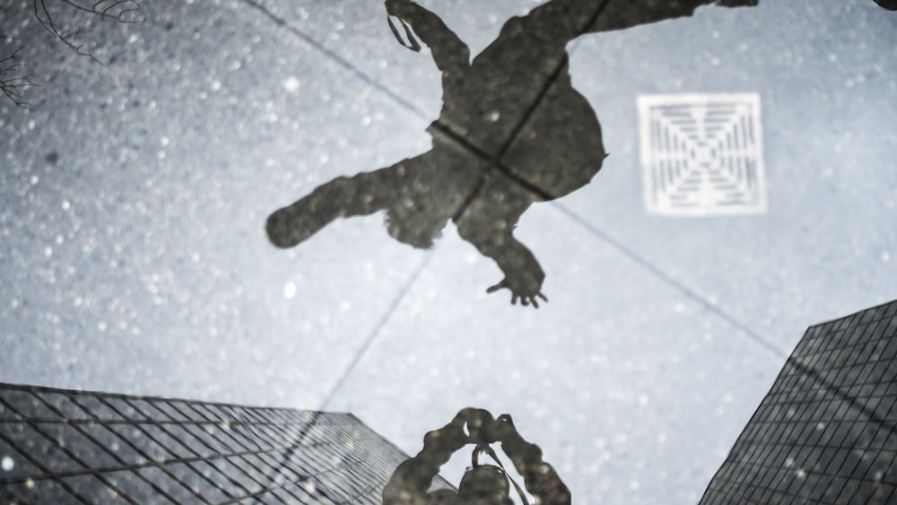 Réflexions dans une flaque d’eau d’un photographe et d’une personne sautant