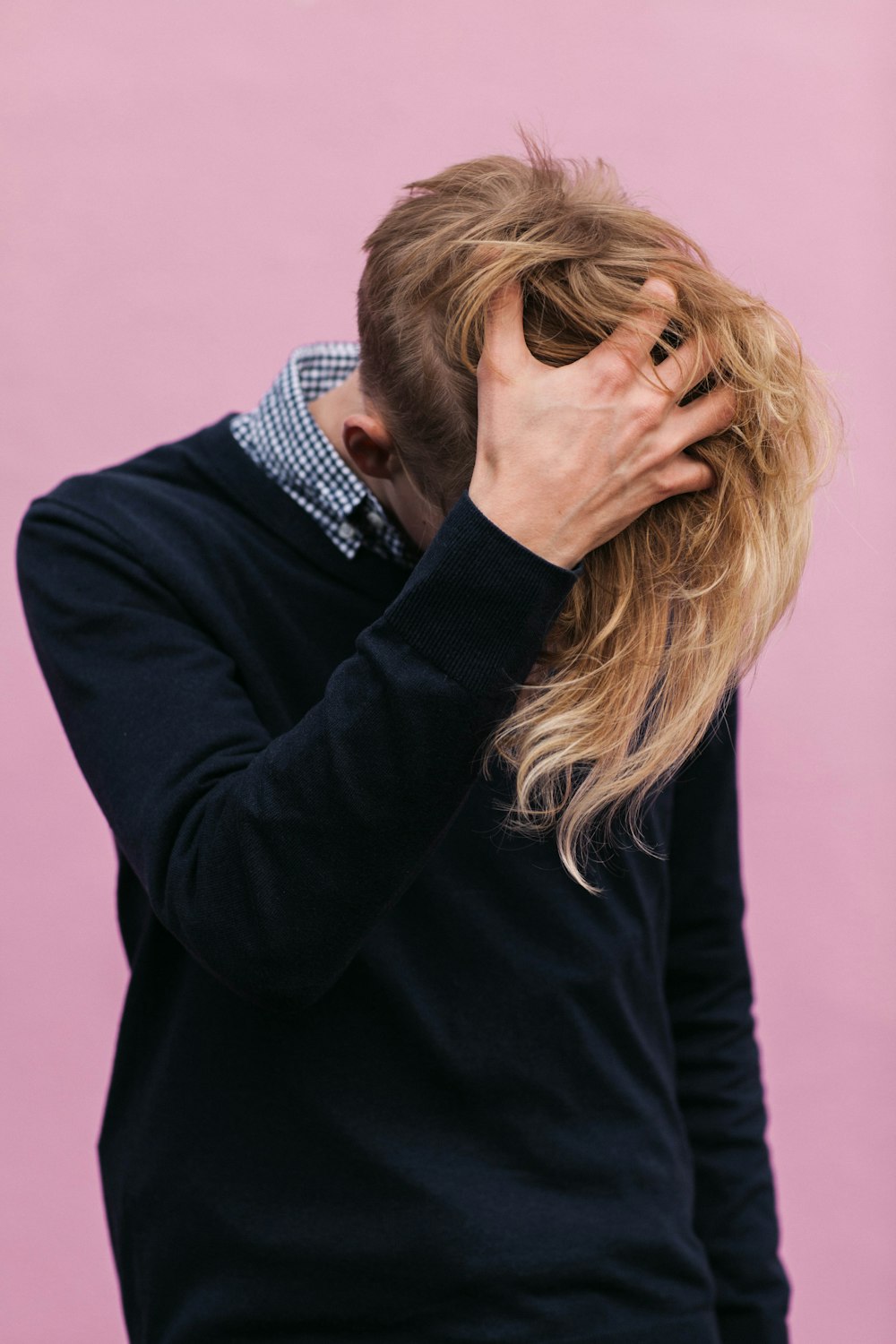 homme portant un sweat-shirt noir à col rond avec une main dans les cheveux