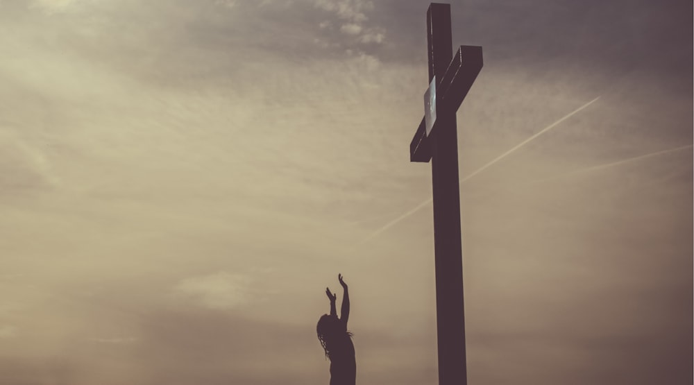 A cross with a cloudy sky background.