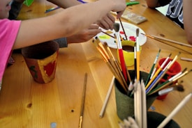 Children painting on easels with smiles on their faces.