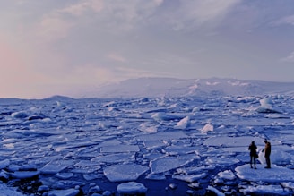 man and woman standing cracked sea ice under gray sky