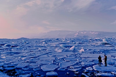 man and woman standing cracked sea ice under gray sky north pole google meet background