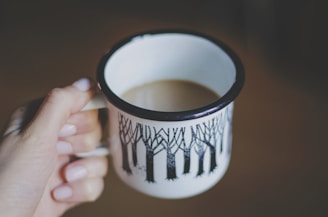 white and black ceramic mug filled with coffee