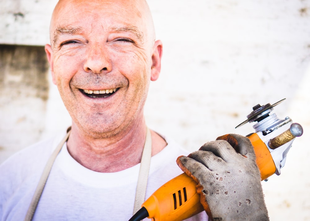 man holding orange angle grinder