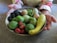 A smiling woman holding a colorful bowl of fresh vegetables and fruits.