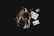 A rustic leather backpack is placed against a dark background, accompanied by a variety of travel-related items. Next to the backpack, there are a journal with handwritten notes, a pen, a passport, loose coins, a small book titled 'El Despertario,' and a neatly rolled-up cord or cable.