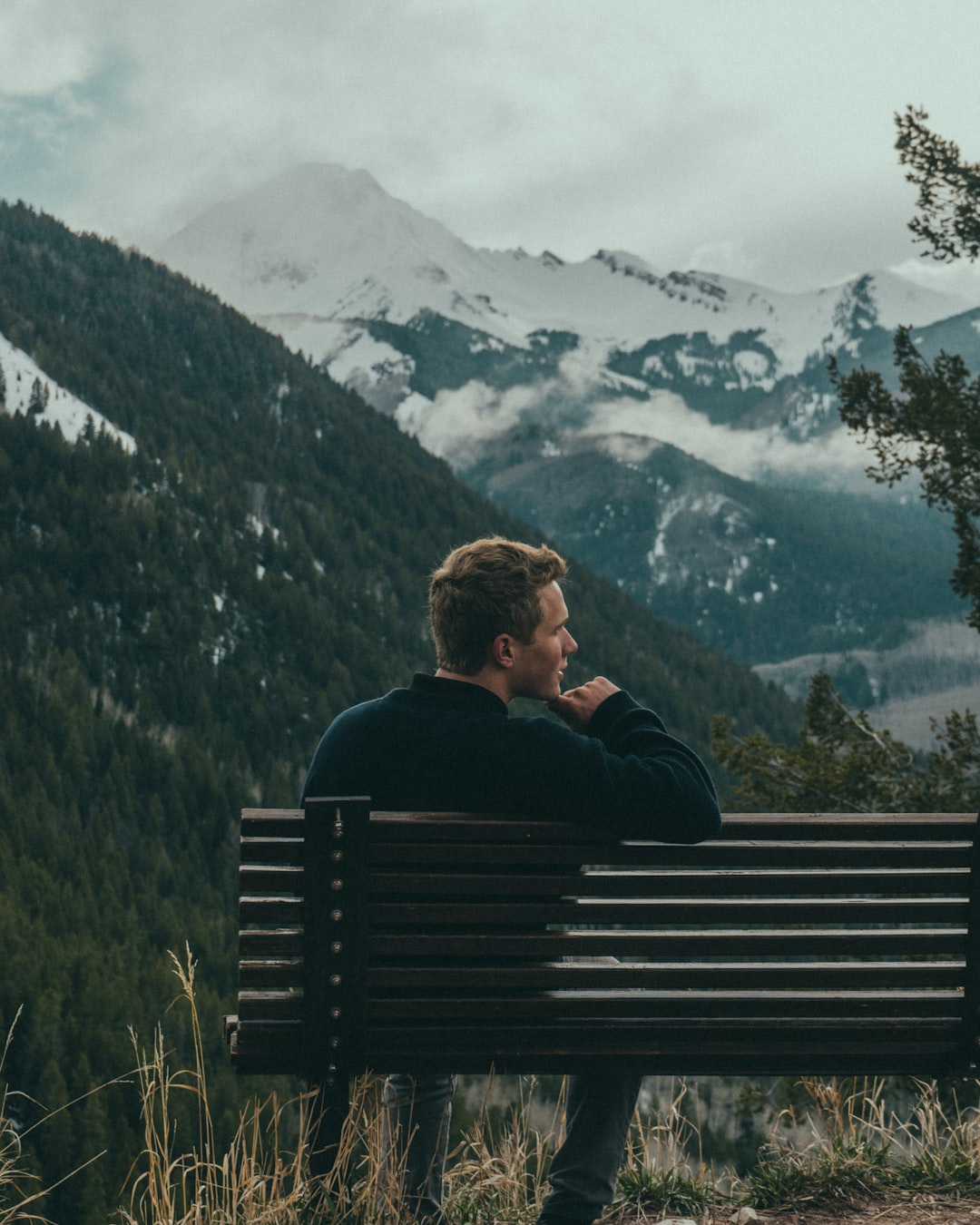 man sitting on bench on top of the mountain