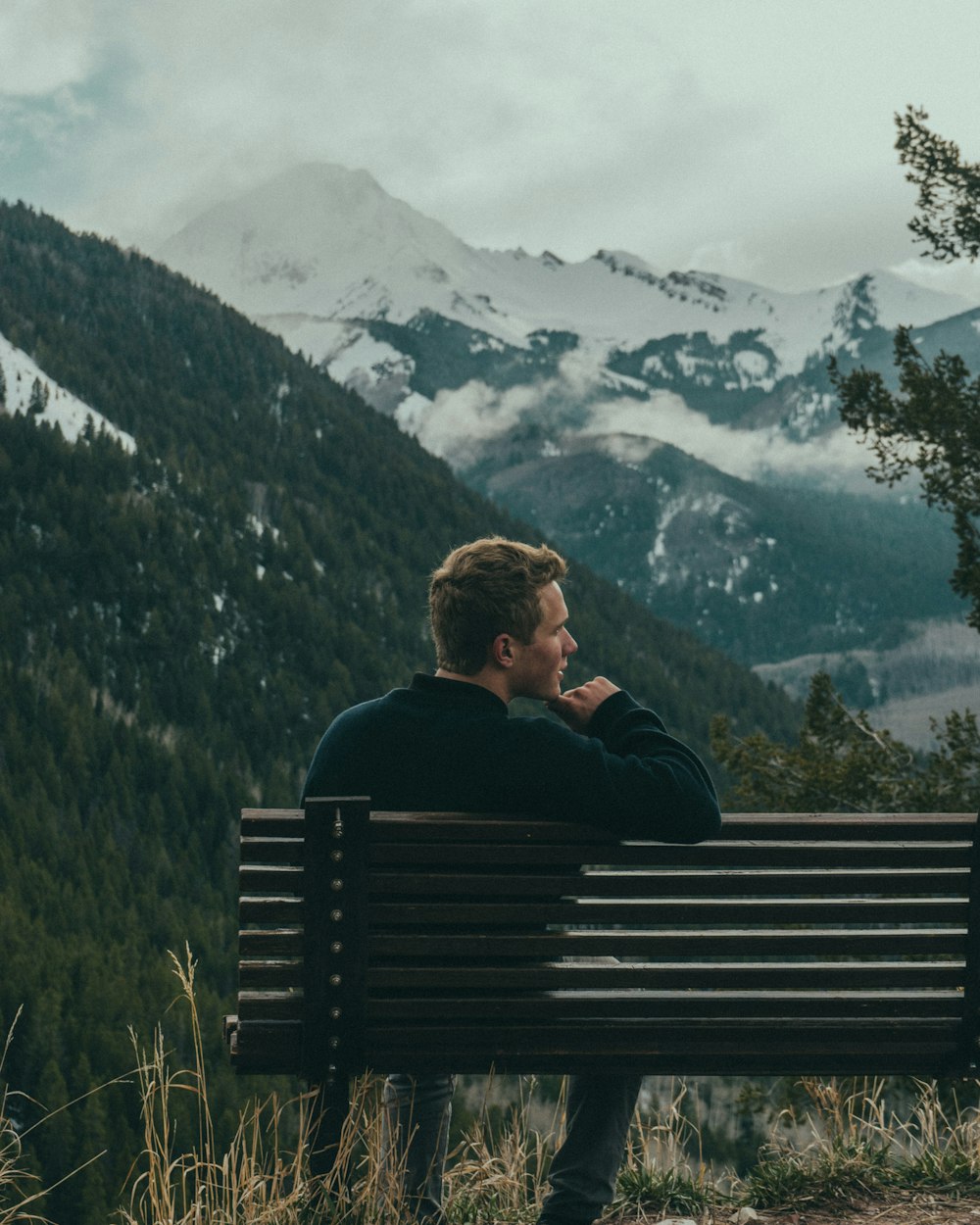 homme assis sur un banc au sommet de la montagne