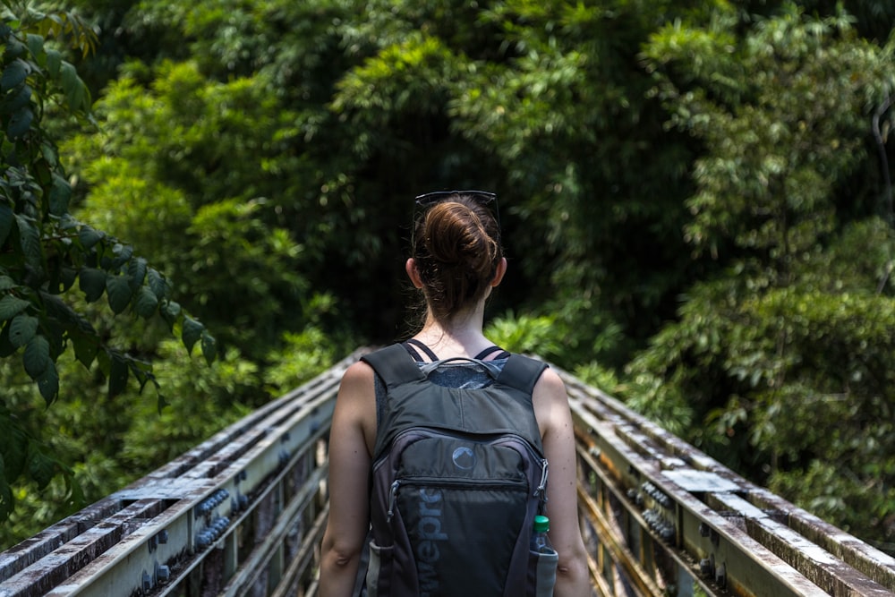 woman wearing backpack walking on bridge