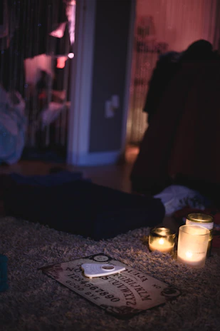 An old, weathered Ouija board resting on a wooden table, softly lit by candlelight.