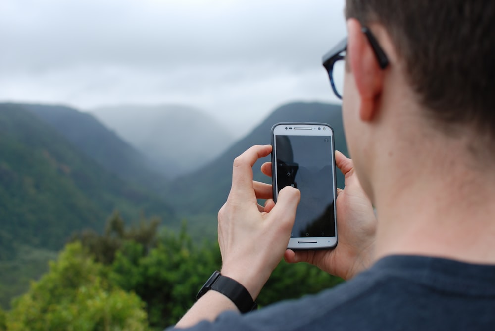 person taking photo of hills during daytime