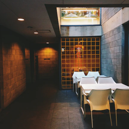 Wide shot of the dining area showcasing clean lines, white walls, and volcanic stone accents under natural light.