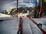 Close-up of winter sports equipment with snow-covered mountains in the background.
