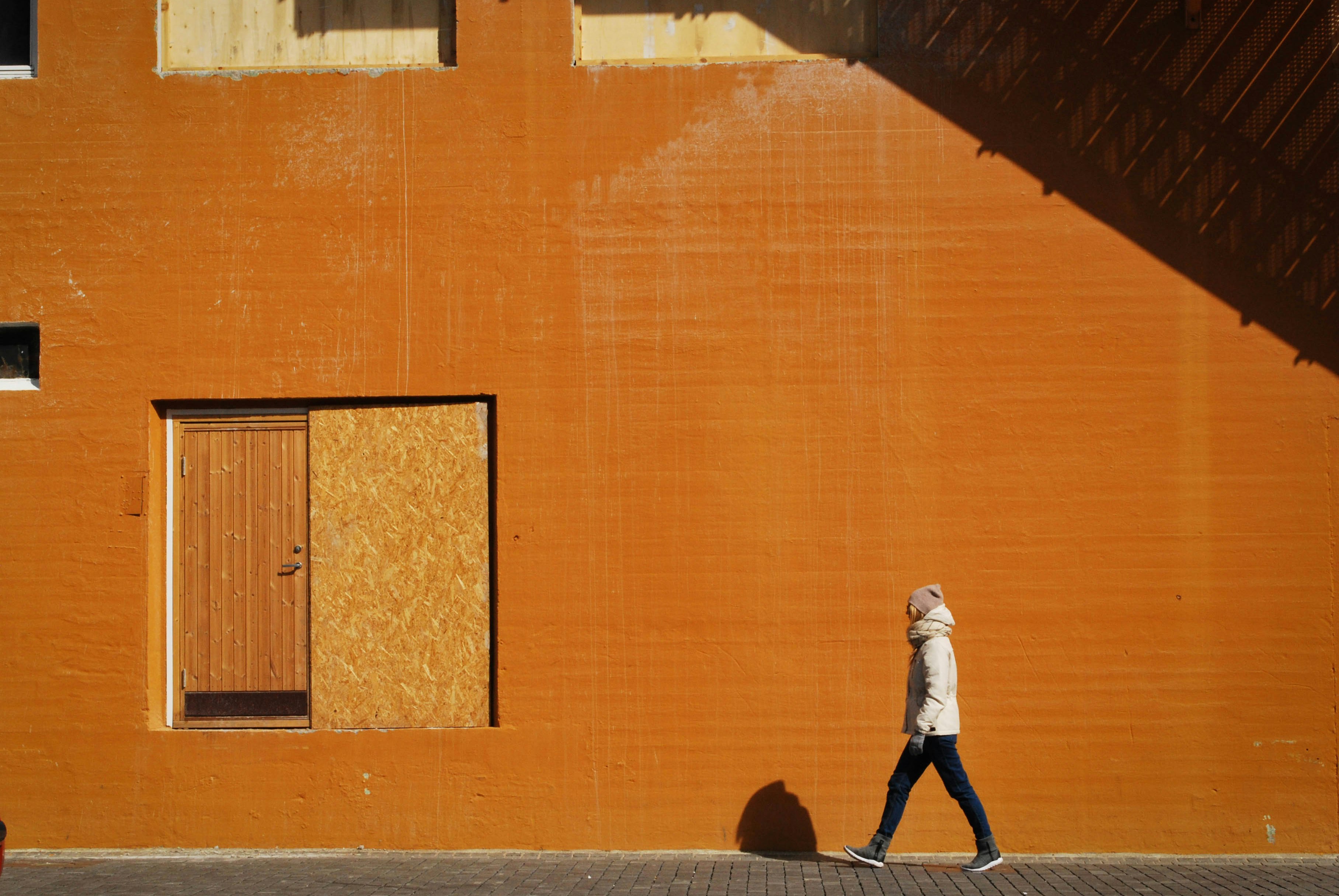 man walking beside orange building at daytime