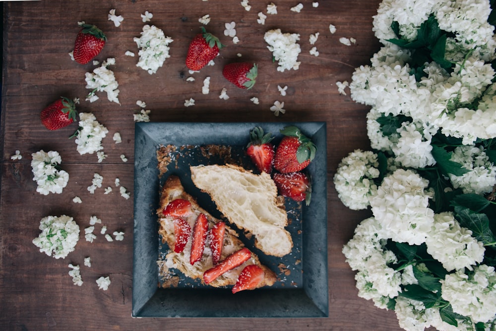 Erdbeersandwich serviert auf weißem Teller neben weißen Blumen