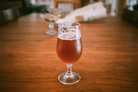 Close-up of frothy beer glasses on a wooden table with warm golden lighting.