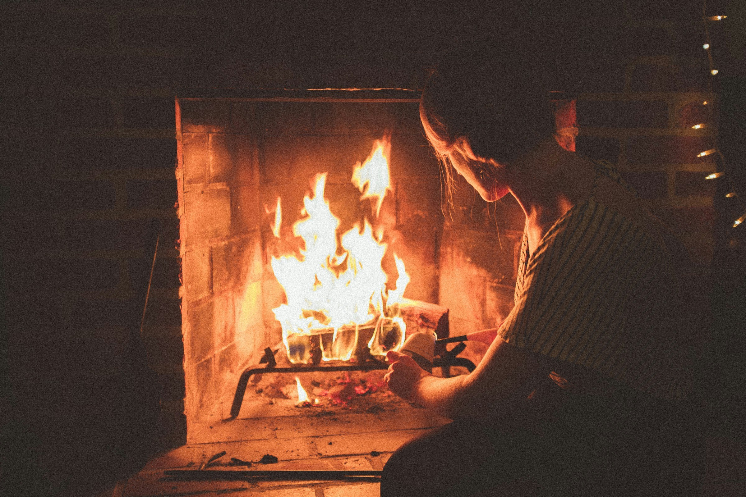 A person in front of a lit fireplace