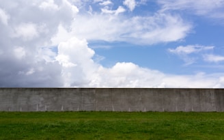 Workers installing a precast concrete boundary wall at a residential property with clear blue skies.