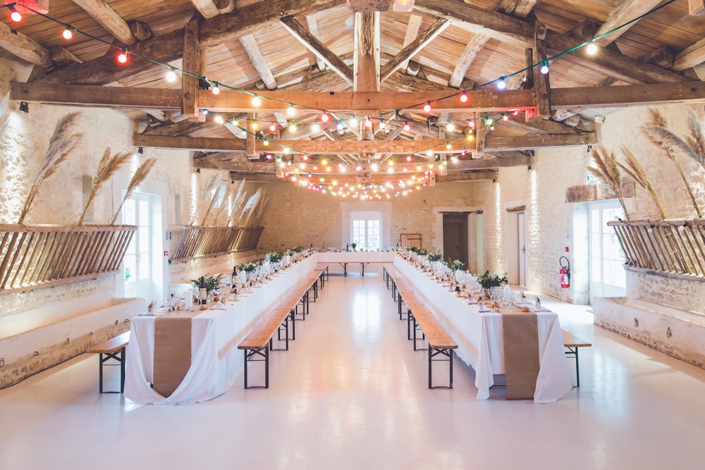 Wedding reception tables with wooden benches and string lights above them at Abbaye de la GrÃ¢ce-Dieu
