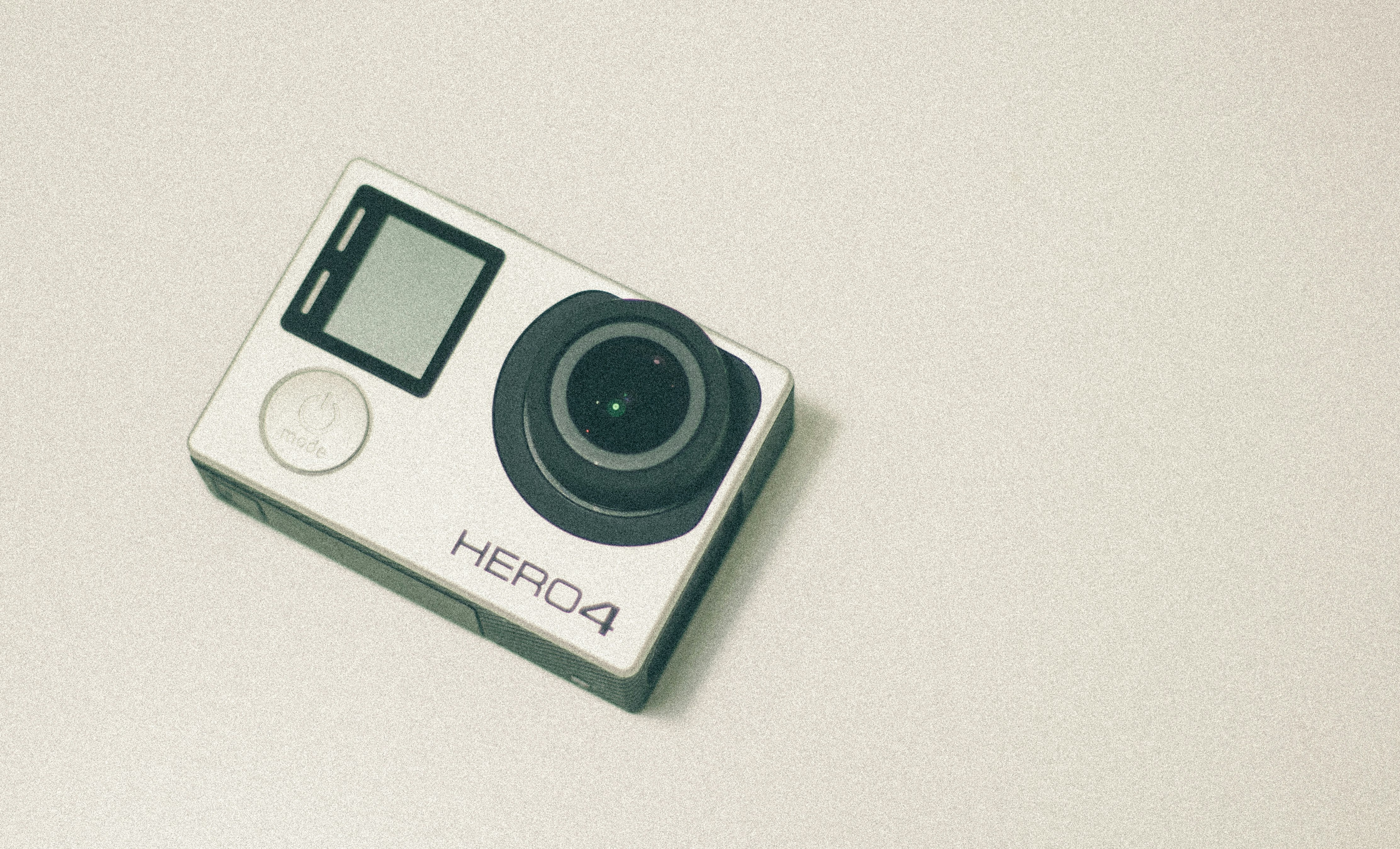 A GoPro Hero4 camera sitting on a white surface.